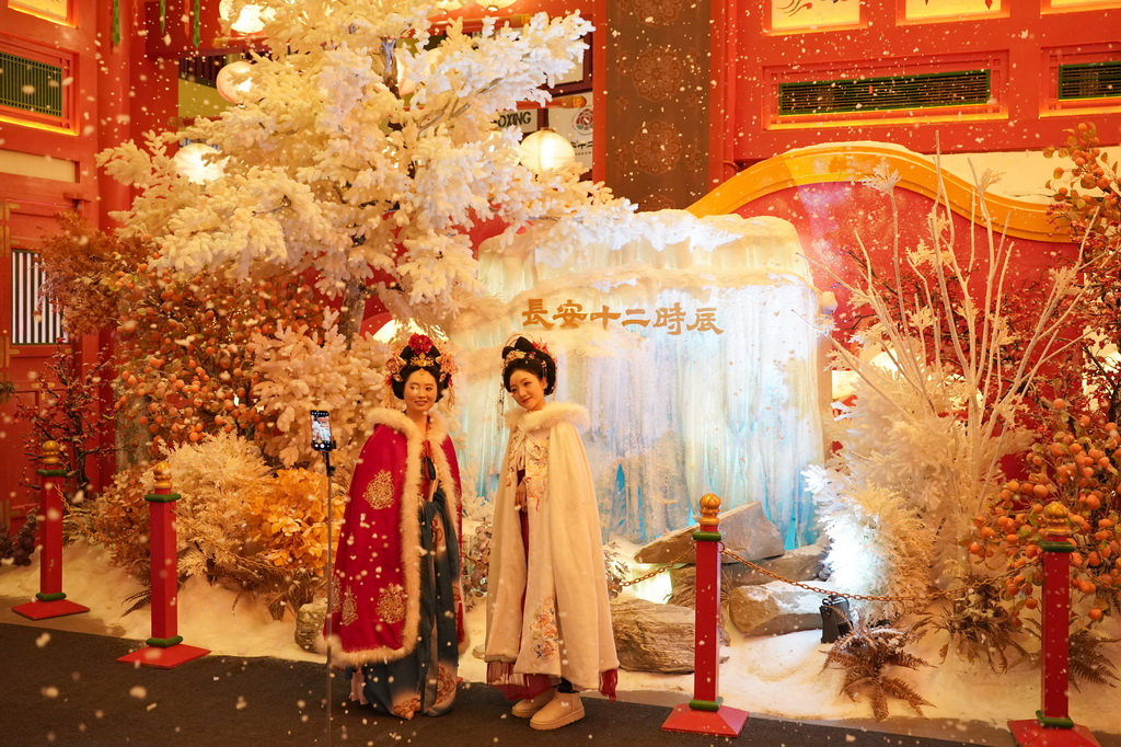 12月23日，游客在街区以冬日长安雪景为主题的场景中拍照。