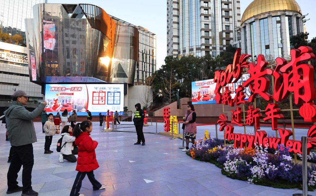 1月3日,市民游客在上海南京东路步行街世纪广场上的春节装饰前拍照。新华社记者 方喆 摄