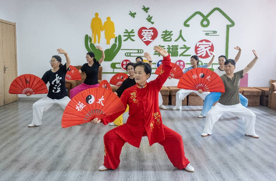 在江苏省兴化市昭阳街道英武社区居家养老服务站,老年人们在学习太极功夫扇。来源:人民图片