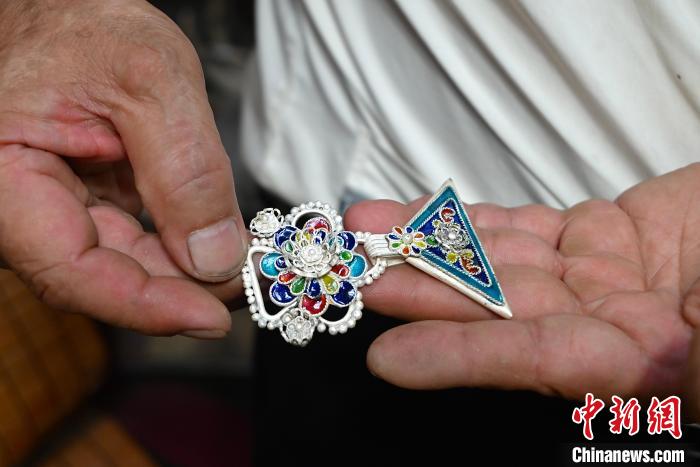 图为吴共能在展示已做好的银饰品。　侯芸莹 摄