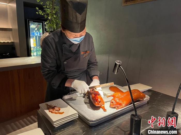 一家烤鸭店内，烤鸭师傅正在“片鸭”。　潘琦 摄