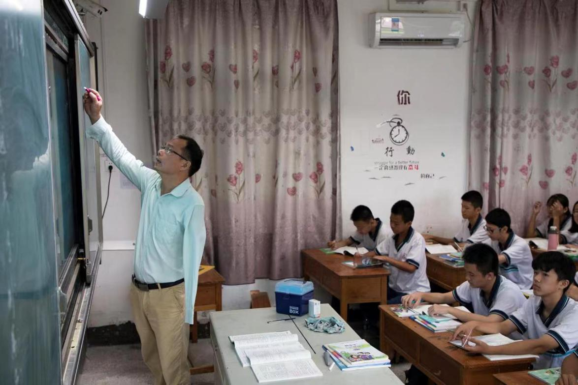 在课堂上,梁木山在给学生们写板书。受访者供图