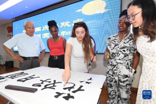 9月28日,在柯桥大渡社区,一名来自突尼斯的客商(中)在社区活动中学习书法。